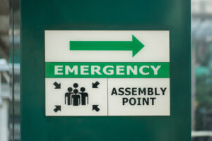 Emergency assembly point sign notifying employees where to go in the event of an emergency after an alarm is verified.